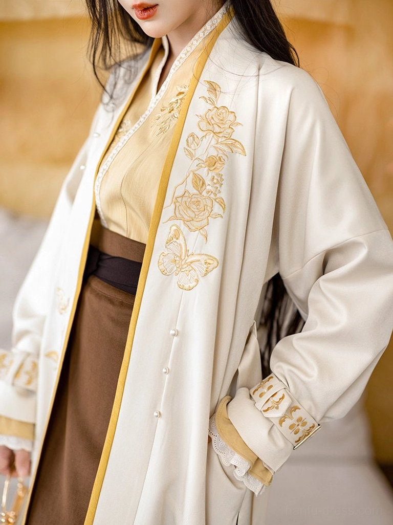Close up of Song Dynasty Hanfu cream outer jacket with pearl buttons, mustard collar trim, and delicate golden floral embroidery