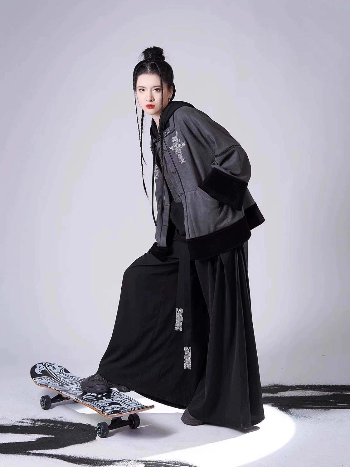 Side profile of a modern Chinese Hanfu outfit showing the cropped grey jacket, black contrast cuffs, wide sleeves, and embroidered flowing pants