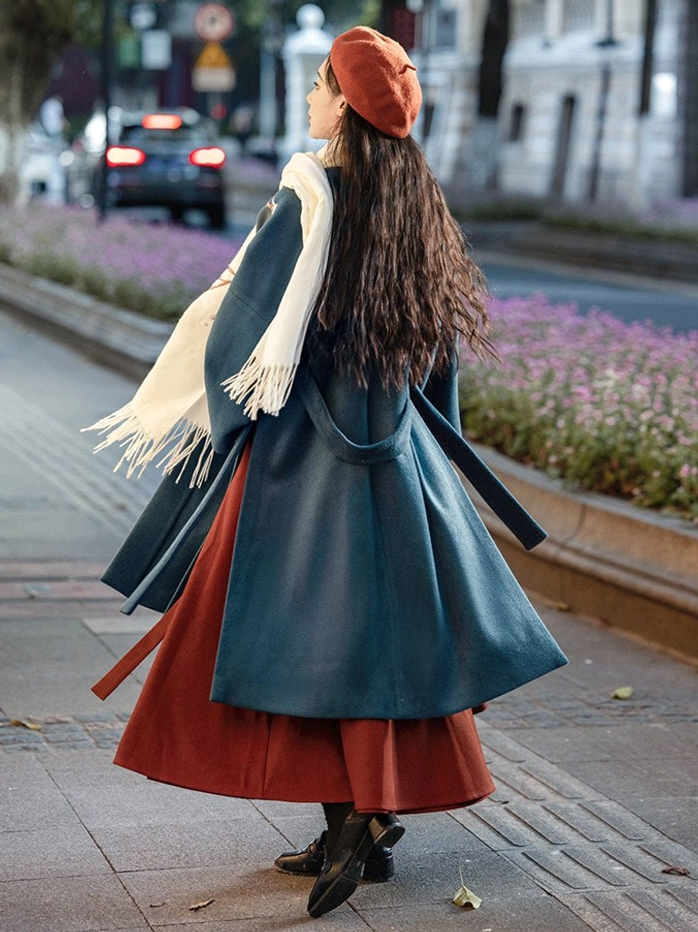 Back view of a Song Dynasty-inspired Hanfu ensemble showing the dark teal embroidered coat with rear waist straps and the flowing burgundy A-line pleated skirt in an urban setting
