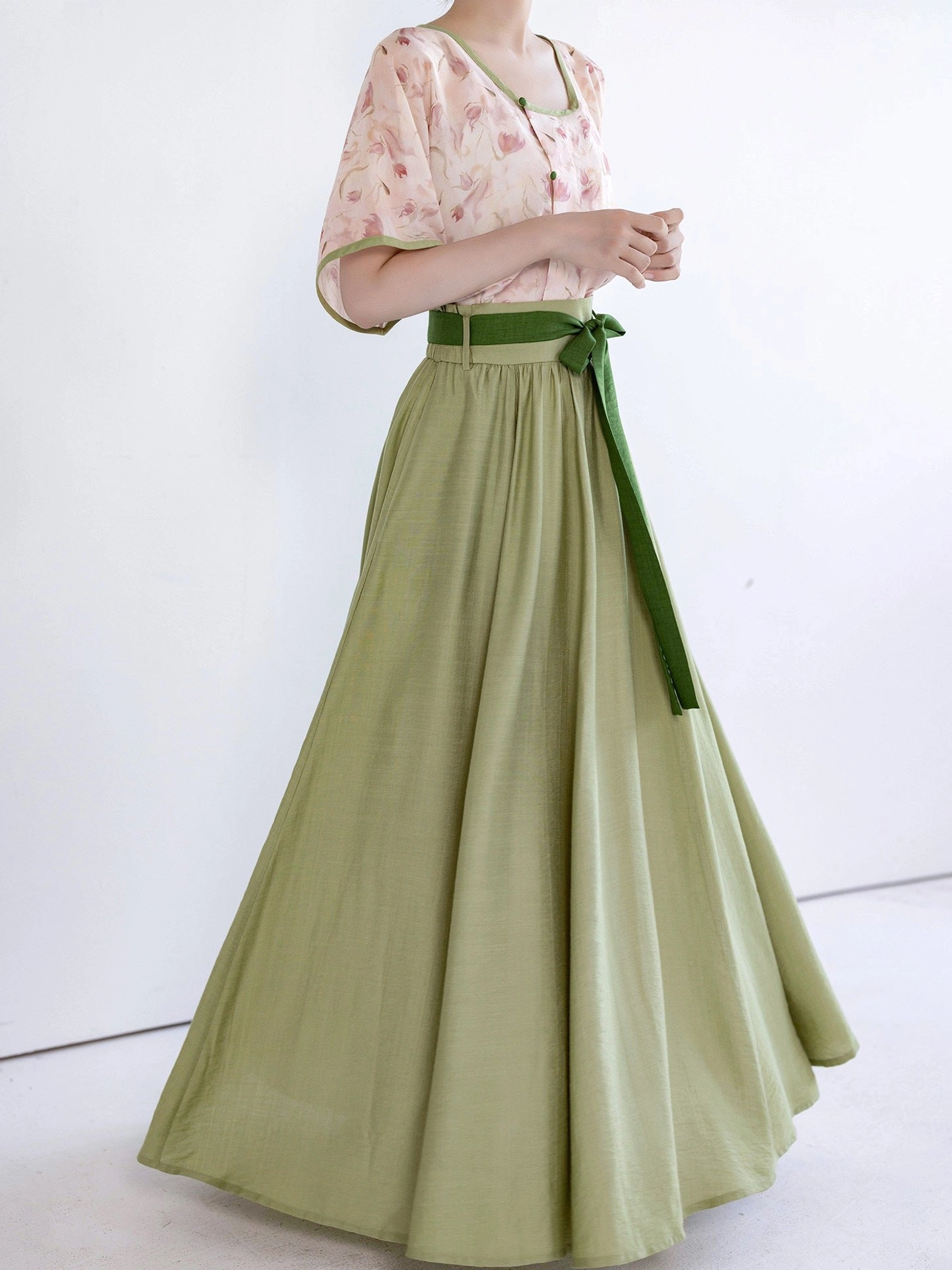 Front view of pink floral Song Dynasty Hanfu top styled with flowing A-line matcha green maxi skirt and dark green waist ties