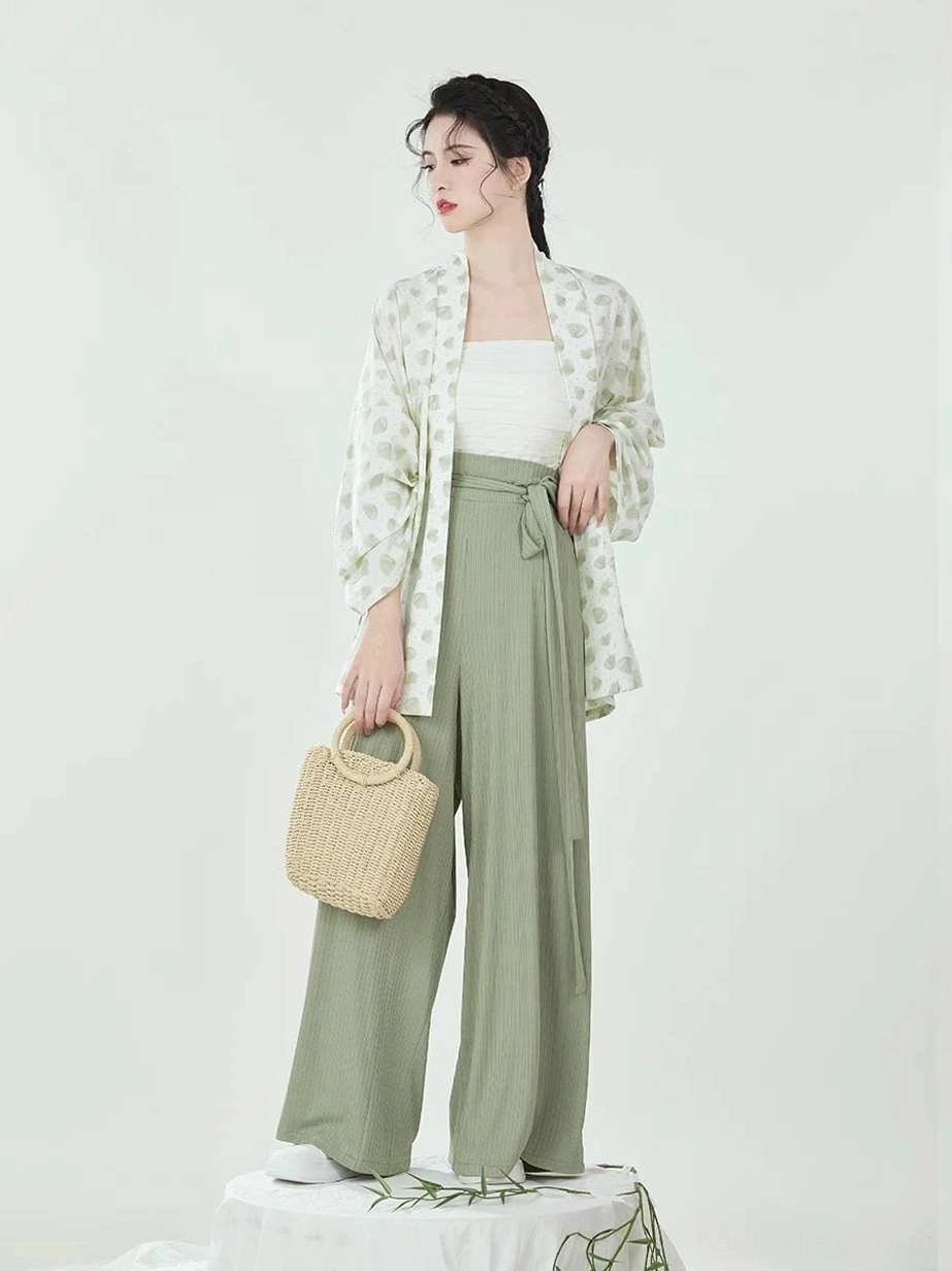 Side view of Song Dynasty modern Hanfu outfit showing flowing winged sleeves, leaf-print outer top, wide-leg pants, and woven tote bag