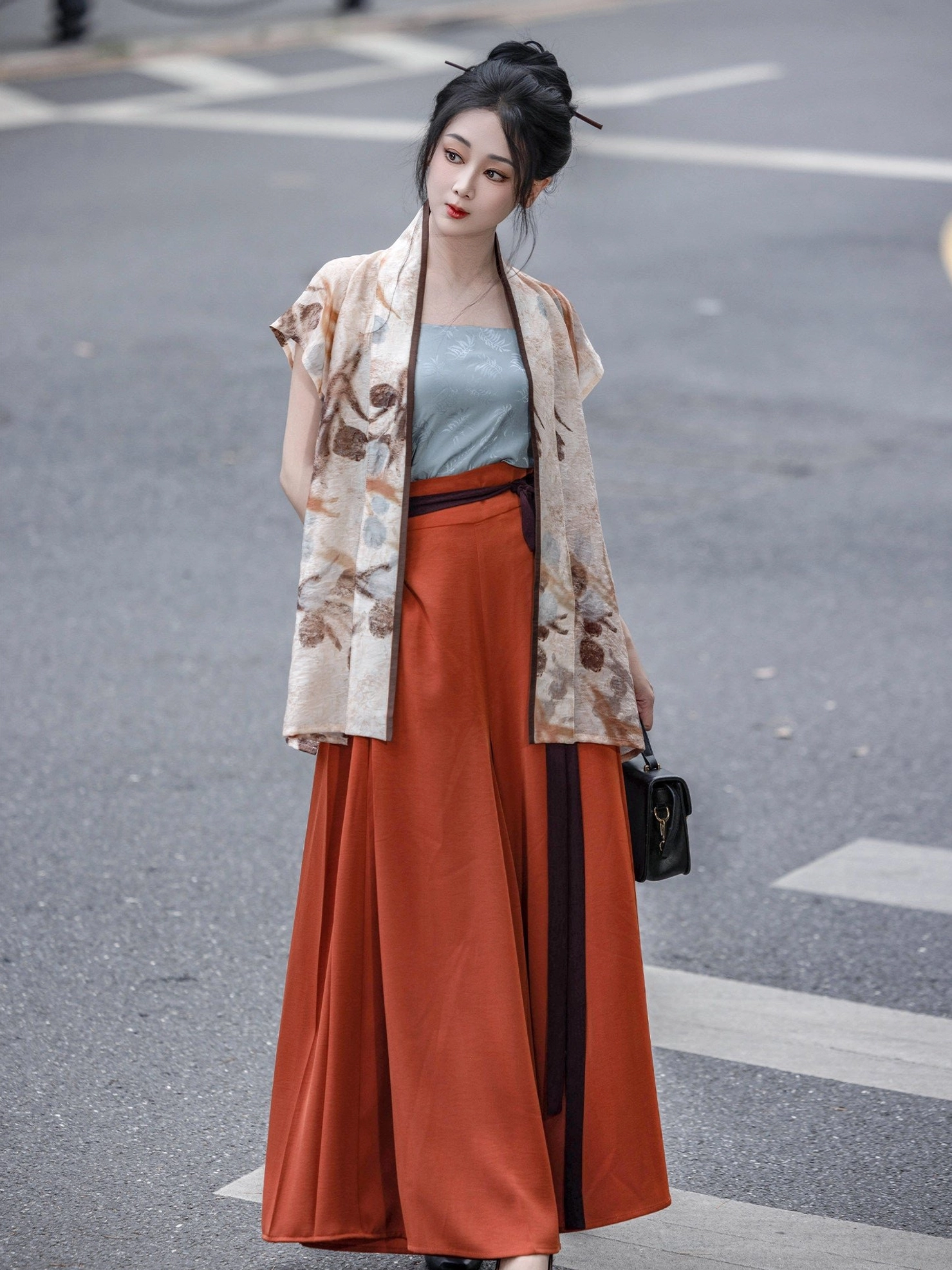 Modern Song Dynasty Hanfu withered flowers winged sleeve top styled with blue camisole and terracotta skirt on an urban crosswalk