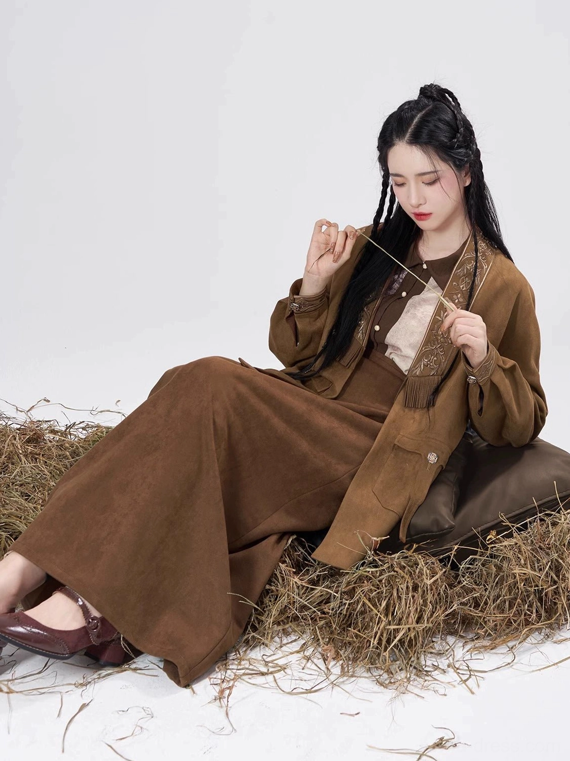 Woman seated in a relaxed Song Dynasty inspired Hanfu outfit with an open brown coat, flowing wrap skirt, and casual layered styling