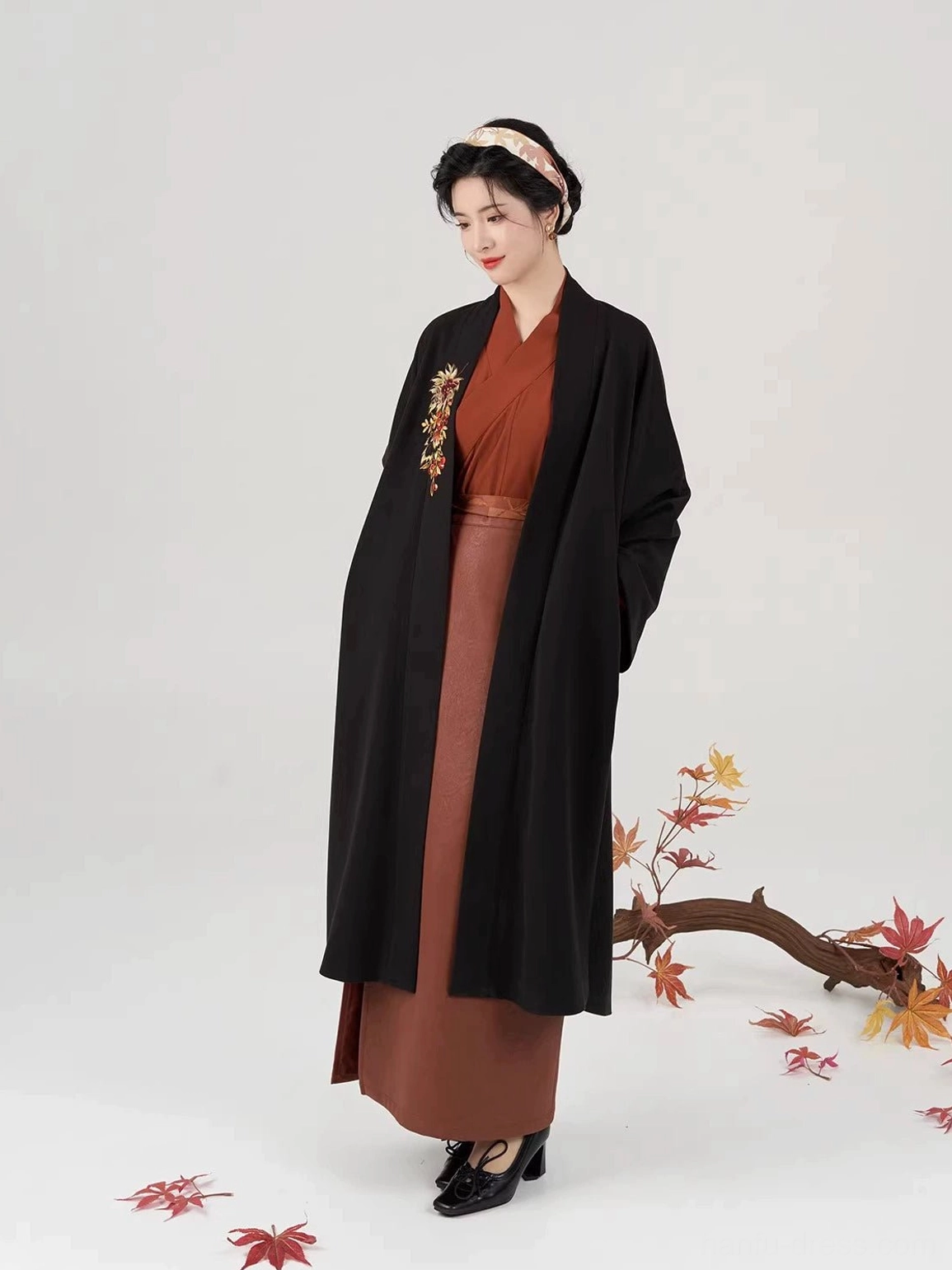 Three-quarter view of a Song Dynasty inspired hanfu outfit with wide sleeves, long black coat, rust-red skirt, and matching traditional headband