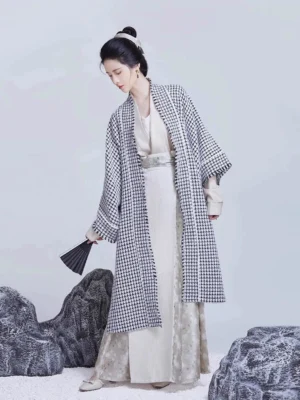 Song Dynasty modern Hanfu set with houndstooth beizi jacket, off-white inner top, three-pleat wrap skirt, wide sleeves, and black folding fan in a minimalist Chinese-style studio