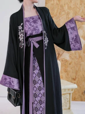Side detail of a Song Dynasty modern Hanfu outfit showing wide sleeve black cardigan, purple printed cuffs, waist sash, floral embroidery, and diamond patterned wrap skirt