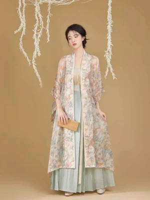 Front view of a woman wearing a Song Dynasty modern hanfu set with a watercolor floral beizi jacket, beige camisole, and sky-blue pleated skirt in a warm studio setting