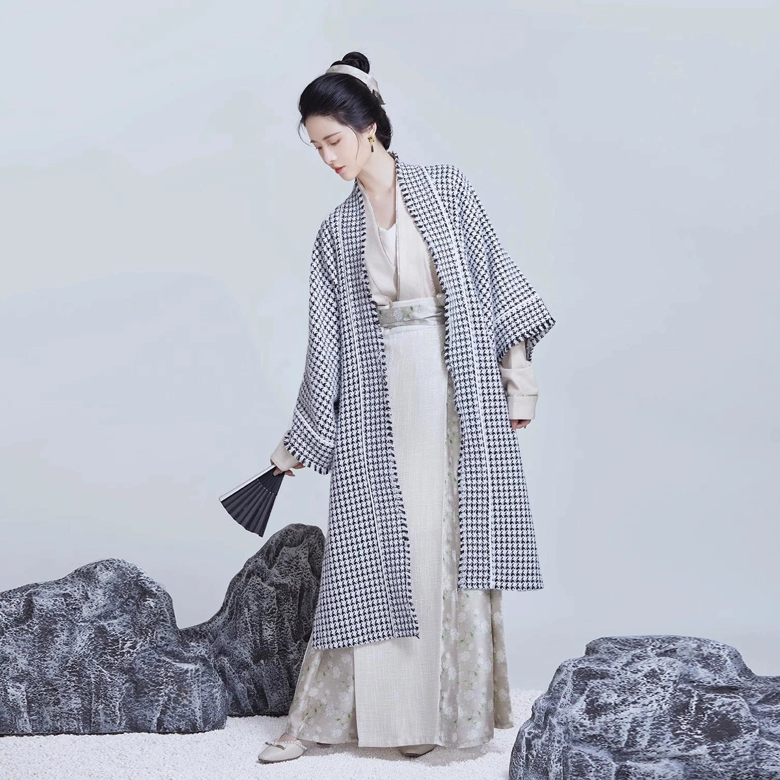 Three-quarter full-body view of a Song Dynasty modern Hanfu ensemble with houndstooth beizi, ivory layered garments, wide sleeves, and black folding fan