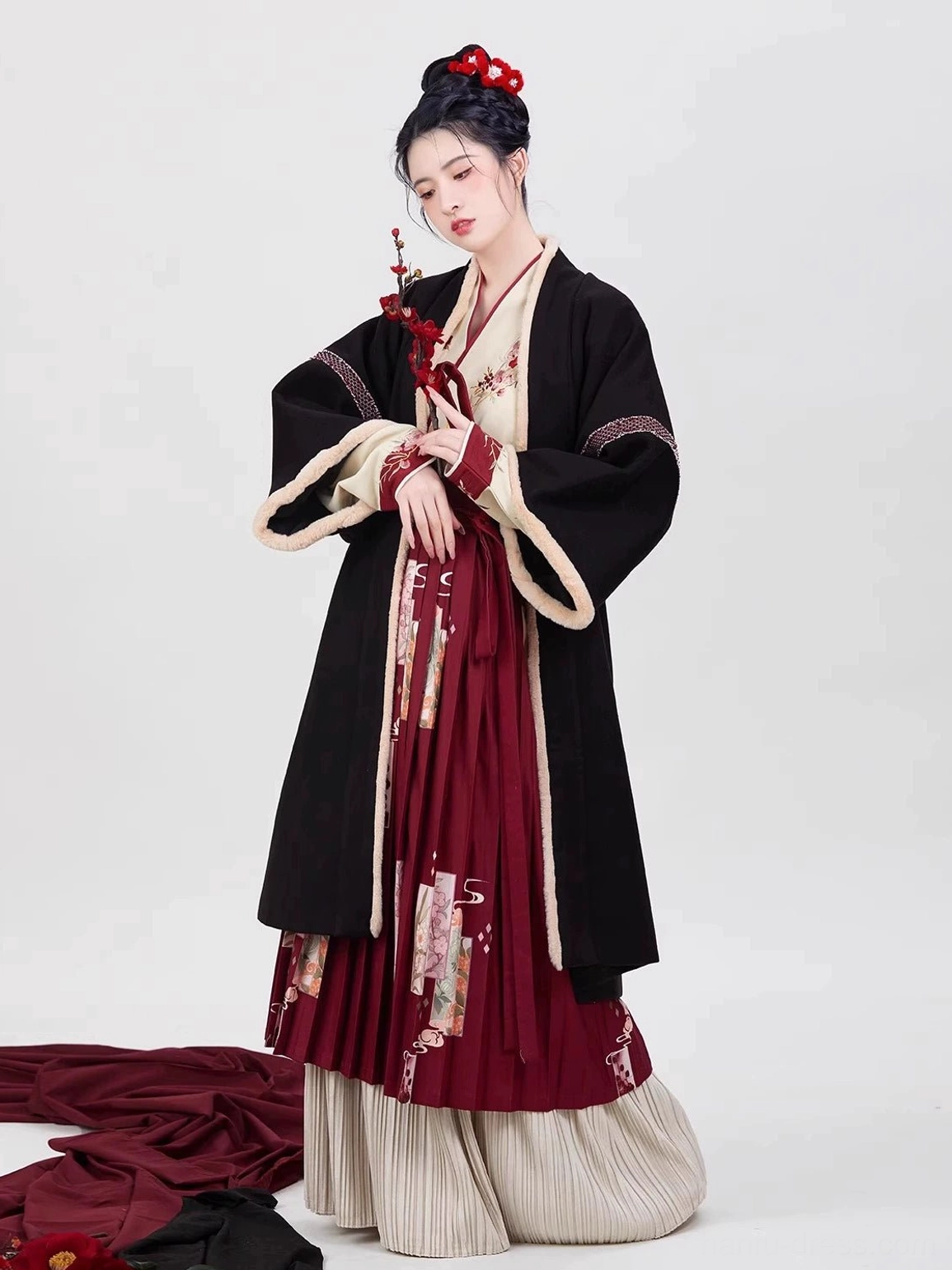 Full-body front view of a Song Dynasty modern Chinese New Year hanfu set with black outer robe, red pleated floral skirt, embroidered inner top, beige trim, and plum blossom hair accessory