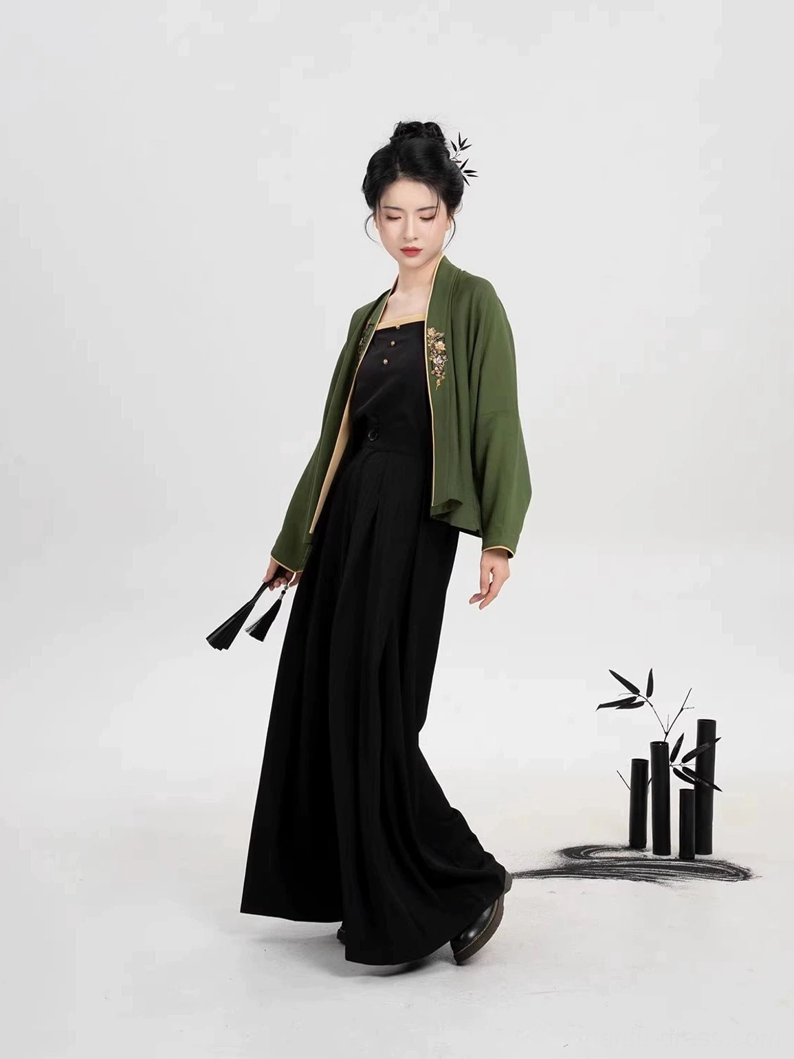 Song Dynasty inspired modern Hanfu outfit shown from the side with green cross collar top black camisole and flowing wide leg trousers