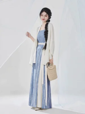 Full-body front view of a woman wearing a Song Dynasty modern Hanfu three-piece outfit with an ivory flowing shirt, sky-blue camisole, two-tone pleated skirt, white waist sash, and woven straw handbag
