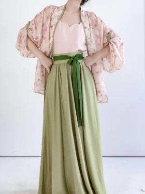 Model wearing a complete modern Song Dynasty Hanfu set with pink floral cardigan, sweetheart camisole, matcha green maxi skirt, and dark green waist sash