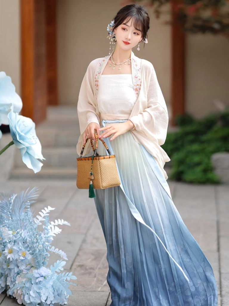 Three-quarter view of Song Dynasty Qiyao Ruqun Hanfu with embroidered beizi coat, blue ombre pleated skirt, and woven rattan handbag near a wooden courtyard staircase