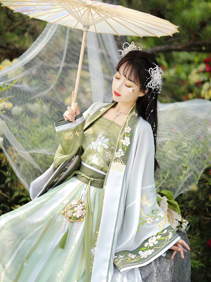 Song Dynasty qiyao ruqun hanfu styled with floral embroidery, silver traditional hair ornaments, green and white layered garments, and a classic Chinese paper umbrella