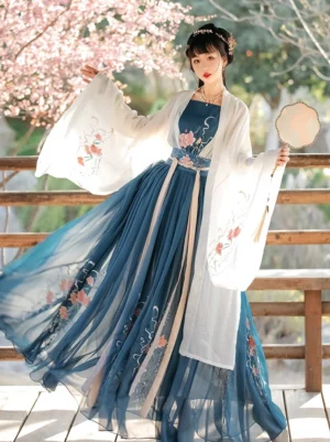Three-quarter front view of a Song Dynasty Qiyao Ruqun Hanfu set with an off-white wide-sleeved robe, peacock blue pleated skirt, pink floral embroidery, and beige waist sashes in a cherry blossom garden