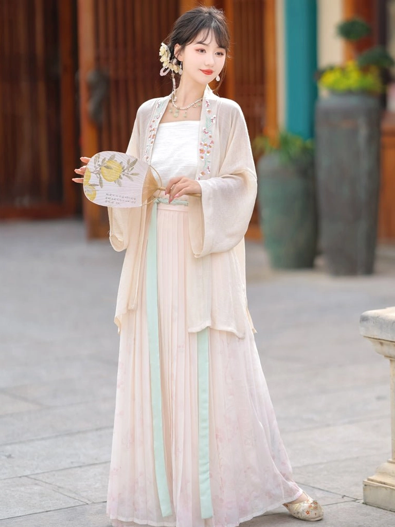 Front view of pink gradient Song Dynasty Qiyao Ruqun Hanfu with cream embroidered coat and flowing pleated skirt in a traditional garden courtyard