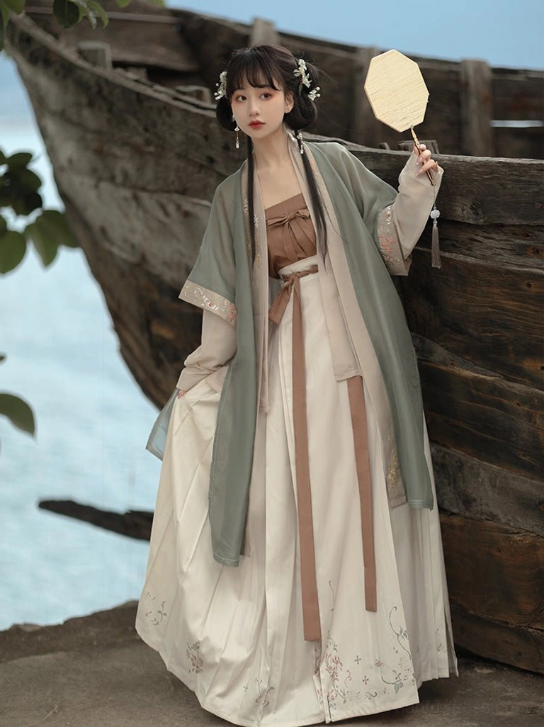 Song Dynasty style Hanfu complete set in sage green sheer beizi with layered sleeves and off-white embroidered skirt beside wooden fishing boat