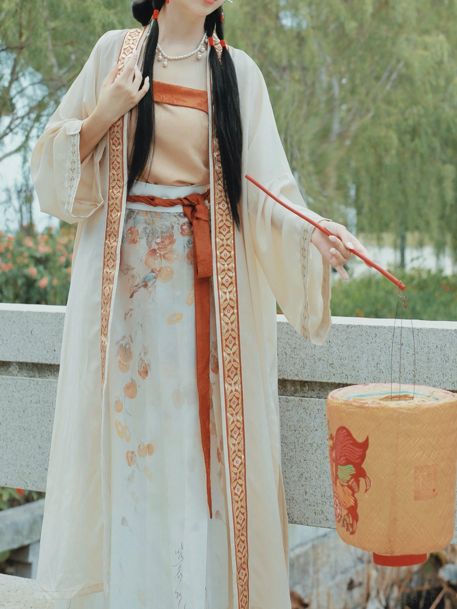 Close-up side view of a Song Dynasty Qiyao Ruqun Hanfu showing the detailed beizi edge trim, pearl necklace, terracotta sash, and persimmon-patterned linen-style skirt near a stone bridge and willow trees