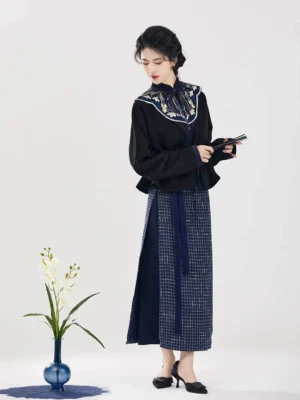 Modern Song Dynasty hanfu set with black embroidered stand collar top and navy plaid wrap skirt shown in a three quarter front studio view