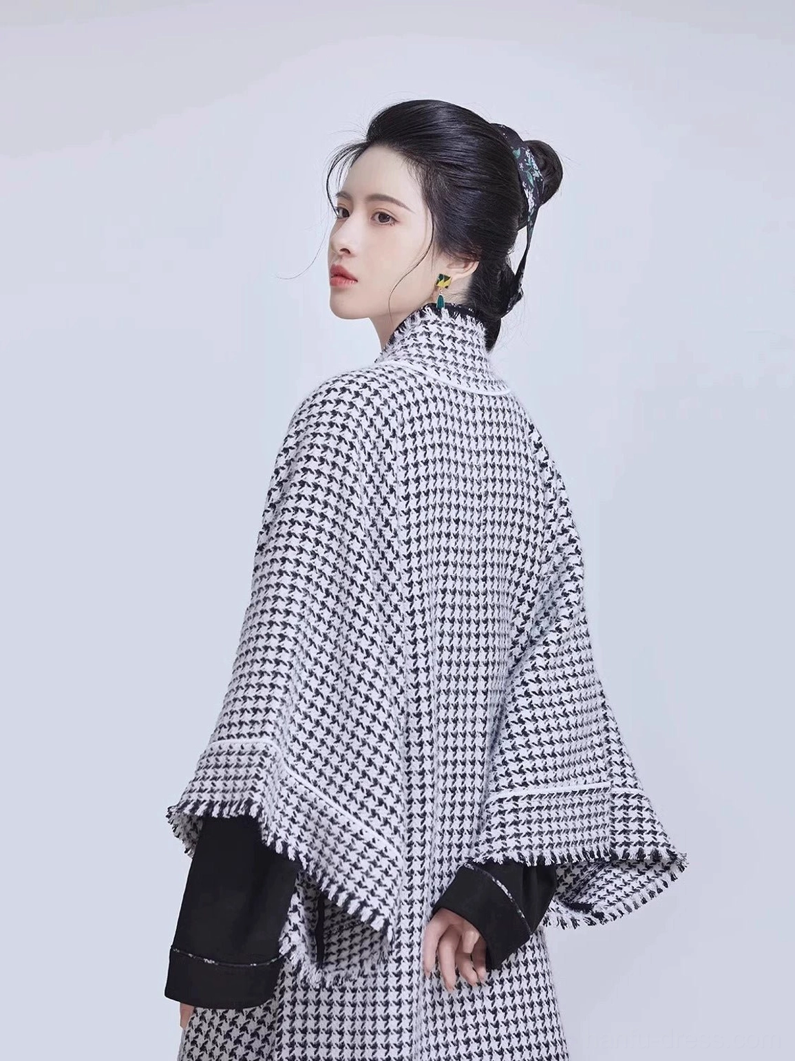 Rear three-quarter view of a Song-style houndstooth beizi Hanfu jacket with wide sleeves, black cuffs, white edging, and a relaxed long silhouette