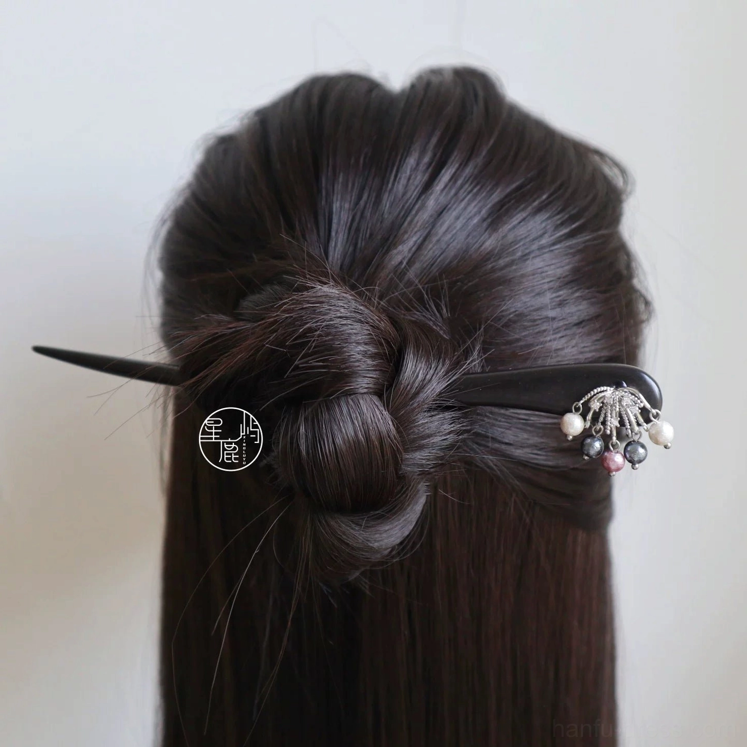 Back view of a neat low bun secured with a traditional Chinese Hanfu hair stick featuring elegant bead tassel pendants