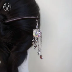 Model wearing a dark brown Chinese hair stick in a braided bun with an iridescent crystal pendant and star moon tassels