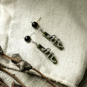 Chinese Spirit Snake drop earrings with dark green rectangular pendants, black beads, and pearl accents on linen fabric
