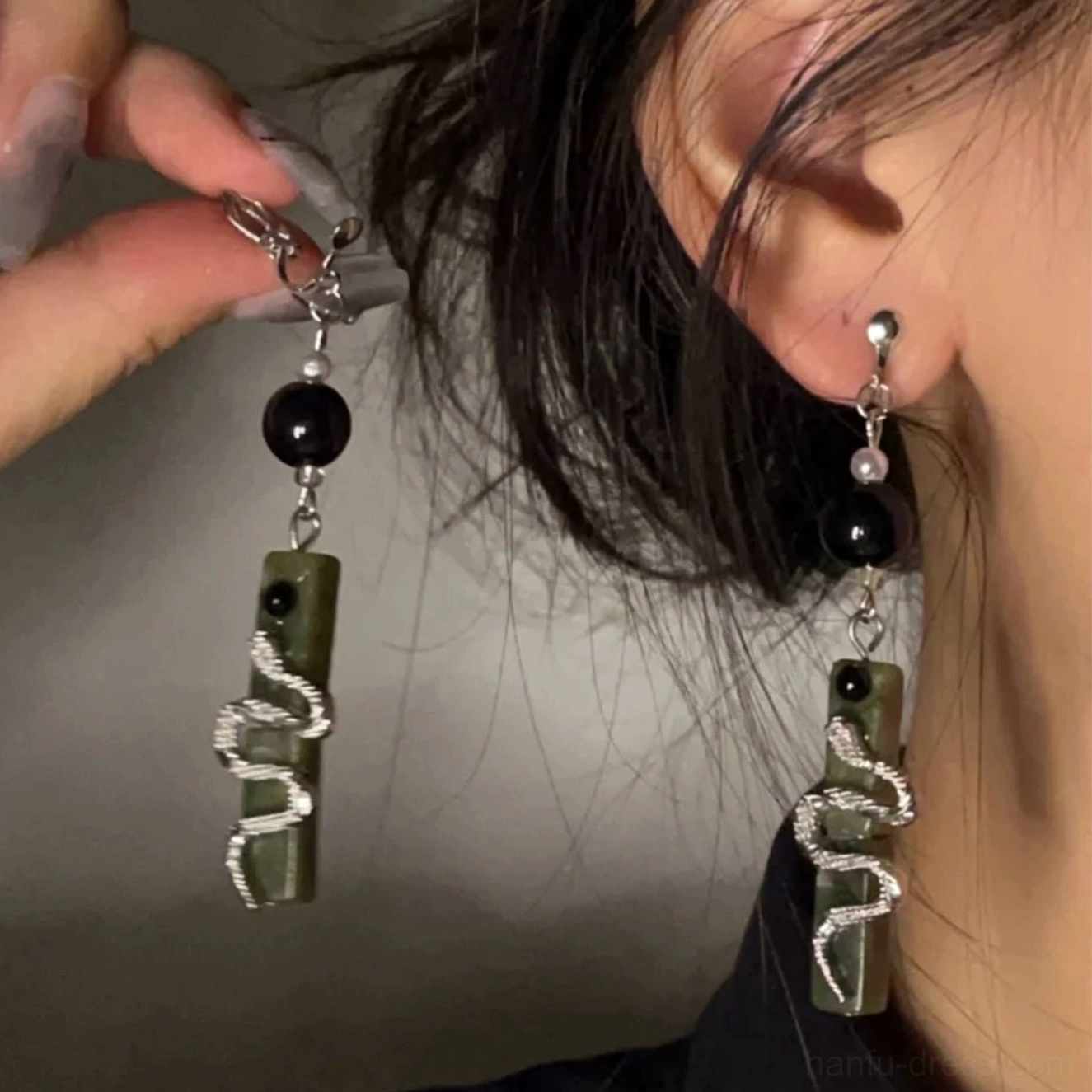 Spirit Snake green drop earrings worn on an ear showing the elegant hanging length and comfortable clip-on style