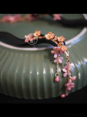 Spring Banquet floral tassel Chinese hair stick displayed on a green ceramic tray with dark wavy wood pin, gold-tone flowers, pink pendant and bead tassels