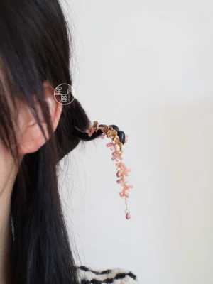 Woman wearing Spring Banquet traditional Chinese hair stick in long black hair, showing the elegant pink floral tassel hanging from a secured updo