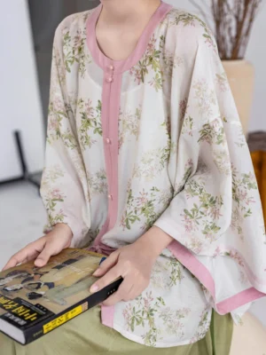 Close-up of Spring Branch modern Ming Dynasty Hanfu floral round collar top with pink frog buttons and contrast trim