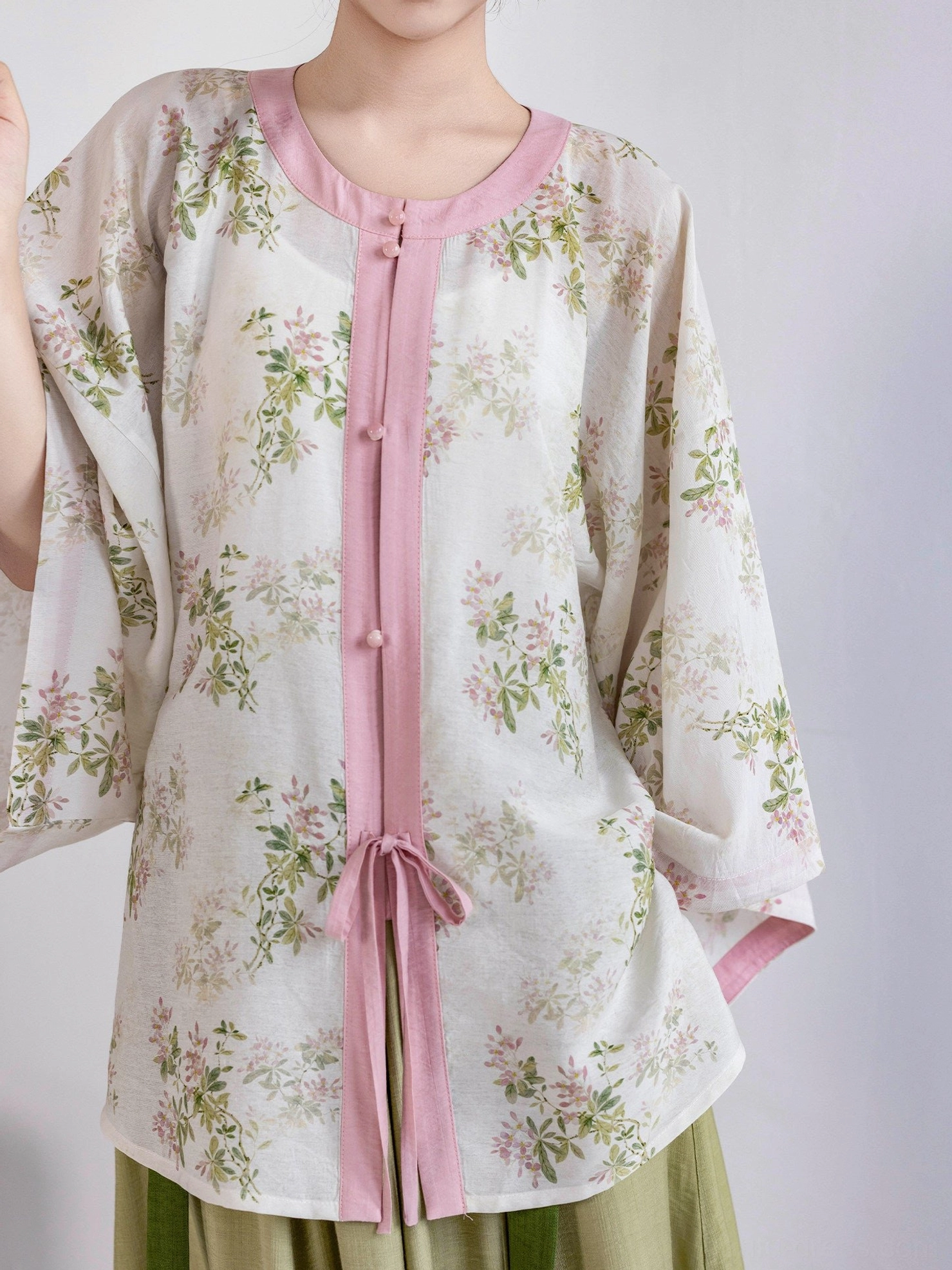 Upper body detail of ivory floral Ming style Hanfu round collar top with pink binding tie closure and green skirt