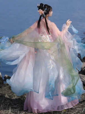 Back view of a woman in a Tang Dynasty style Hanfu Heziqun complete set showing delicate floral embroidery, layered gradient skirt, long flowing scarf panels, and sheer outer sleeves