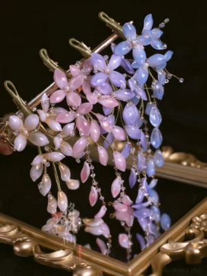 Ombre pink and blue wisteria glass hair pins with waterdrop petals and dangling crystal bead branches displayed on a vintage gilded tray