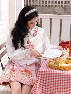 Strawberry cake Hanfu cropped top and pink mini mamianqun shown in a seated garden picnic styling with embroidered doll collar and ruffled cuffs