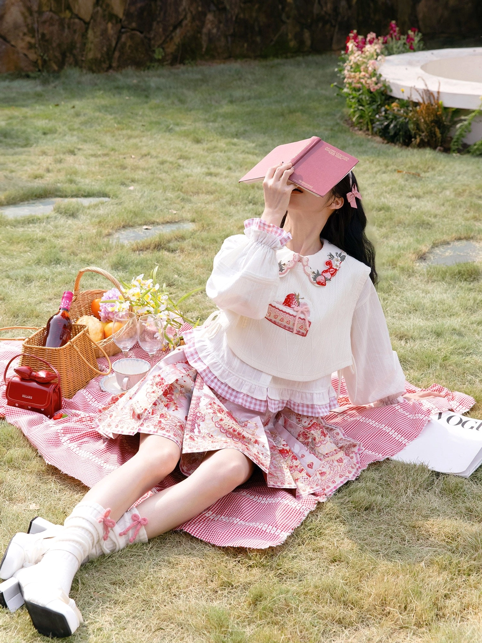 Full outfit view of strawberry dessert modern Hanfu with white ruffled cropped blouse and pink pleated mini mamianqun on a lawn picnic