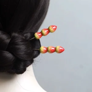 Strawberry trio Chinese hair sticks displayed in a traditional coiled bun hairstyle, featuring red and green strawberry ornaments and slim silver-tone pins
