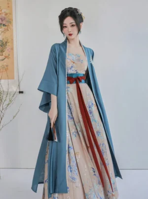 Female model wearing a complete Summer Dream Song Dynasty Hanfu set with dusty blue Beizi jacket, apricot floral Mamian-inspired dress, red waist sashes, and traditional hairstyle in a Chinese-style studio