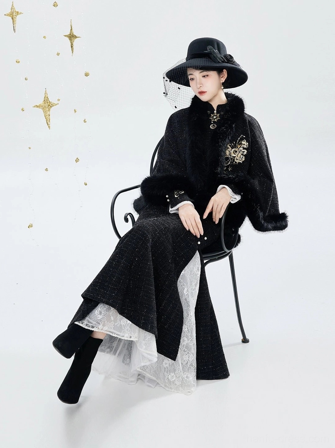 Side seated portrait of Sun and Moon embroidered qipao dress with gold floral details and plush-trim cape cloak