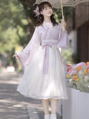 Lavender purple sweetheart modern Hanfu dress with cross-collar top, lace midi skirt and bow waist sash outdoor front view