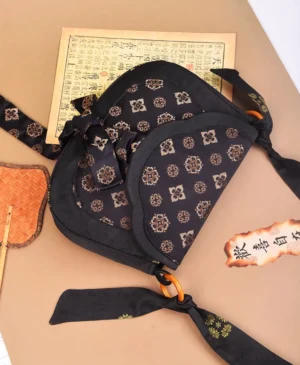 Top view of black Tang Dynasty inspired Chinese crossbody bag with gold floral brocade pattern, double flap and patterned shoulder strap
