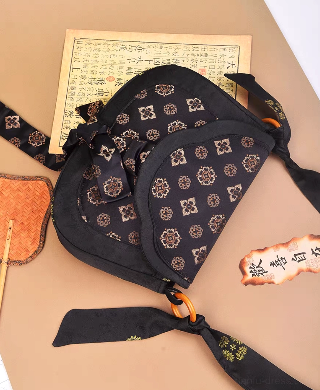 Top view of black Tang Dynasty inspired Chinese crossbody bag with gold floral brocade pattern, double flap and patterned shoulder strap