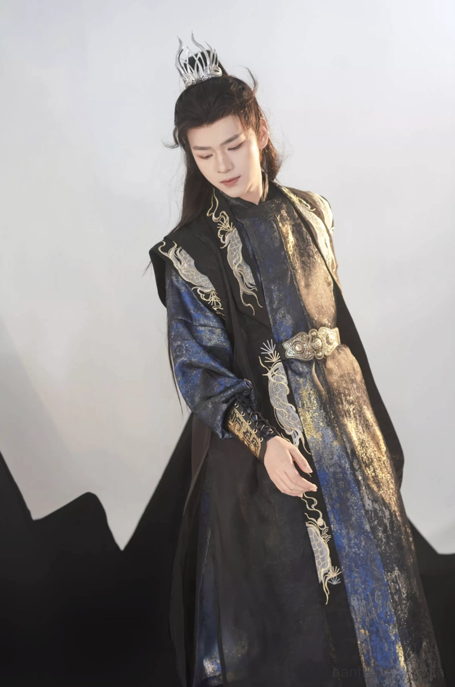 Close front three-quarter view of a male Tang Dynasty hanfu set with visible gold dragon embroidery, ornate metal-style waist belt, embroidered wrist guards, and layered navy and black robe