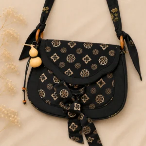 Tang Dynasty floral brocade Chinese crossbody bag in black and bronze gold with bamboo ring detail, printed bow and gourd charm front view