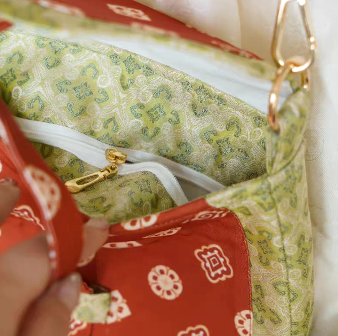 Interior view of Tang Dynasty floral Chinese crossbody bag showing the green patterned lining, spacious compartment, and built-in zipper pocket with gold-tone slider