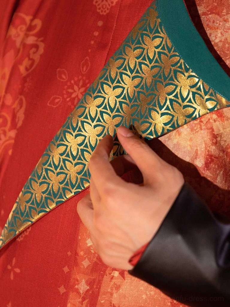 Close-up of teal green collar with gold floral embroidery on Tang Dynasty groom reddish-orange wedding hanfu robe