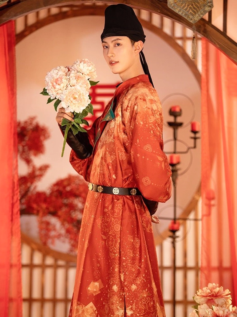 Three-quarter side view of Tang Dynasty groom wedding hanfu in reddish-orange floral round-collar robe with teal embroidered collar and black waist belt