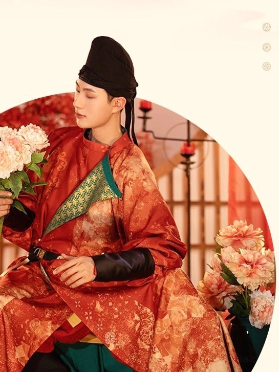 Seated side portrait of groom wearing reddish-orange Tang Dynasty wedding hanfu round-collar robe with embroidered teal collar