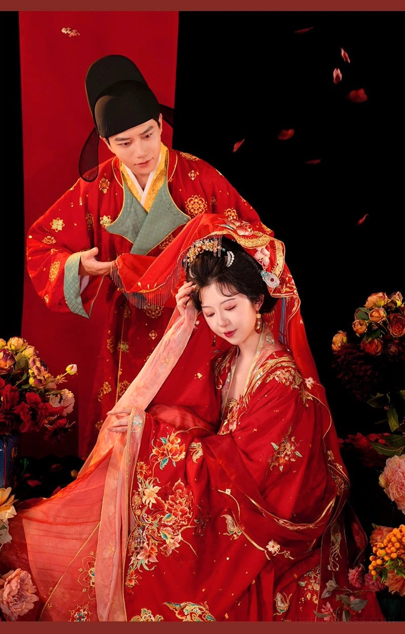 Tang Dynasty Hanfu bride wearing a richly embroidered scarlet wedding gown and sheer red veil while the groom assists with the traditional bridal veil ceremony