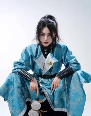 Close up seated view of a Tang Dynasty inspired reversible hanfu coat showing contrasting lapel panel, black leather waist belt, braided arm guards, and decorative brooch